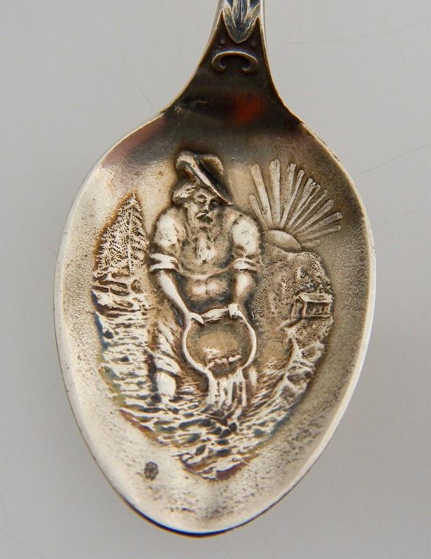 Souvenir Mining Spoon Bowl Dawson City Yukon Canada.jpg - SOUVENIR MINING SPOON DAWSON CITY YUKON - Sterling silver demitasse spoon, 4 3/8 in. long, embossed miner figure panning for gold in bowl, handle marked DAWSON with a miner holding a pick at top, ca.1900, reverse with Sterling marking and maker’s mark of P. W. Ellis & Co. Toronto Canada (1877 -1928) later absorbed by Henry Birks & Sons of  Montreal in 1928, weight 12 gms. [When news first broke of gold being discovered in the Yukon, what became immortalized as the Klondike Gold Rush of 1896-99 kick started a mass influx of prospectors into the small northern town of Dawson City.  Founded in 1897, and fittingly named after noted Canadian geologist George M. Dawson, Dawson City became the heart of the Klondike Gold Rush and the capital of the Yukon, the center of activity for the thousands upon thousands of prospectors who flooded in each year. The hope of striking it rich was more than enough to stir the imaginations of an estimated 100,000 men and women who risked life and limb to make their fortune in the northern capital. Built up seemingly overnight, Dawson City was little more than a remote trade outpost at the dawn of the Gold Rush, with the first settlers forced to sleep in tents and under their own wagons. The town that became Dawson City grew exponentially over the next few years.  Constructed mainly out of wood, and where extra expense could be spared, capped in pressed tin, the town included false fronts and wooden sidewalks.  Before long, Dawson City had grown into a proper town, complete with hotels, saloons, banks, and more than one theatre. Faced with what by any route, either by land or sea, was sure to be a journey fraught with peril, thousands of fortune seekers made their way to the Klondike via the infamous Chilkoot Pass, an unforgiving mountain stretch that soon became synonymous with the Klondike Gold Rush. Often carrying more than 100 pounds of supplies on their backs, and outfitted in the extraordinarily inadequate winter clothes and hiking gear of the day, travelers were often forced back by the cold, or simply died along the way. The vast majority of those who made it to Dawson City would leave as ruined souls with not a penny, or nugget, to their name. By 1899, the Klondike Gold Rush was all but over, and the last stragglers and determined hopefuls abandoned Dawson City over the course of the next few years. The peak population of 40,000 in 1898 plummeted to well below 5,000 by 1902. Into the first half of the 20th century, Dawson's fortunes continued to slide. In 1953, Yukon’s official capital was moved to Whitehorse.]